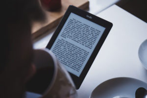 woman reading kindle while drinking coffee