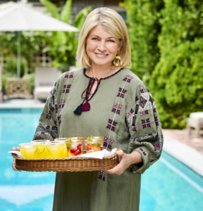 Martha Stewart holding tray of drinks by a pool