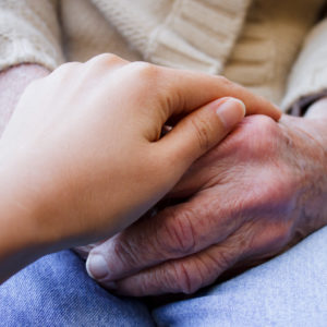 Young caregiver holding hands with senior lady