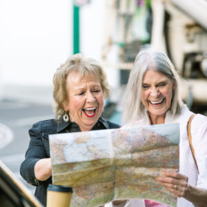 Two 50+ aged white women smiling and looking at a map togeteher